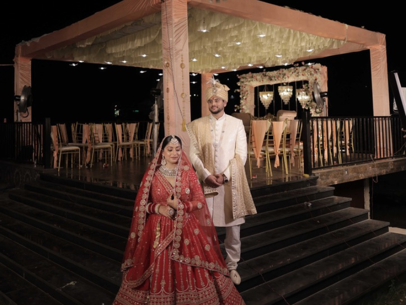 bride and groom posing together in traditional attire near the decorated wedding stage