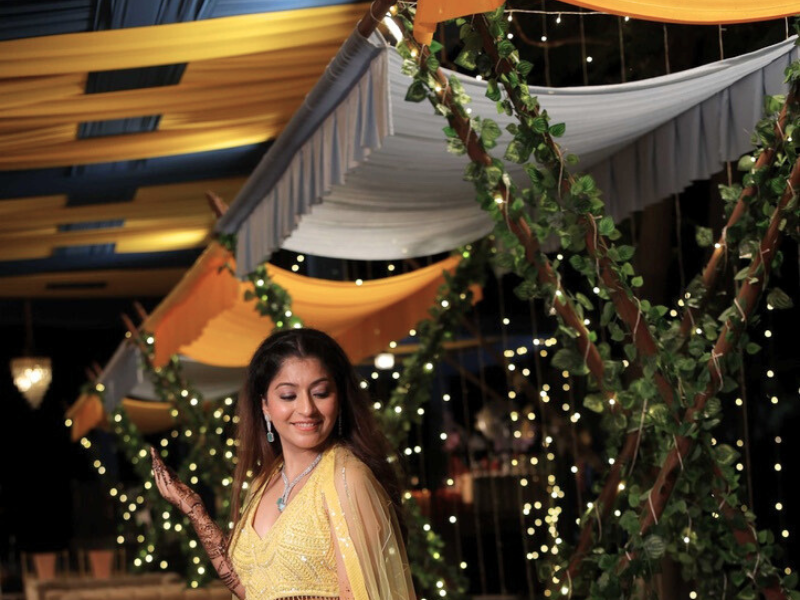 bride in a sparkling yellow lehenga posing joyfully in a vibrant setting with string lights (2)