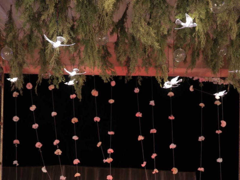 green foliage and glass ornaments hanging under a wedding canopy