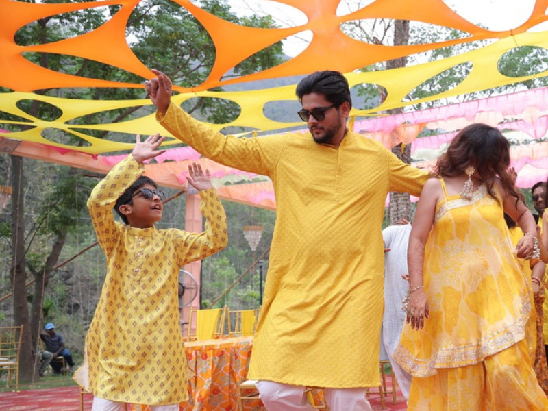 guests dancing joyfully under a colorful canopy with red and blue circular patterns at the haldi ceremony