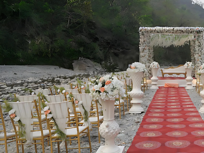 riverside wedding mandap decorated with white and peach flowers under a canopy