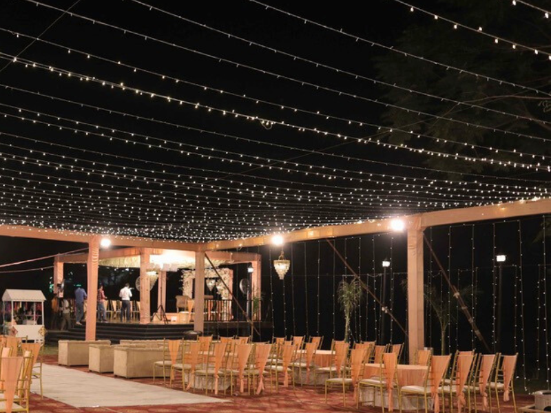 wide view of a beautifully decorated wedding venue with floral mandap and string lights