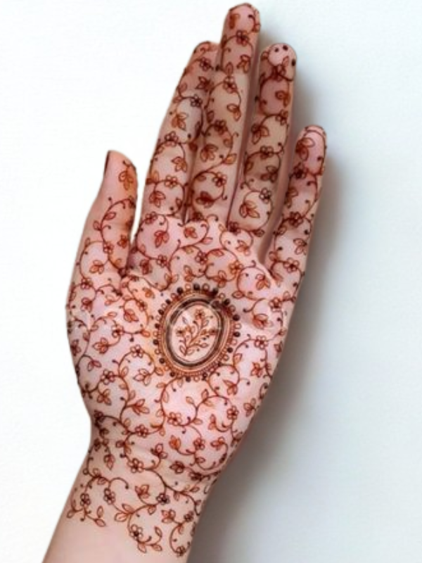 Intricate Mehndi design on the palm featuring a large central mandala with a butterfly motif, surrounded by fine floral and paisley patterns, with additional small butterfly and geometric accents on the fingers and wrist.
