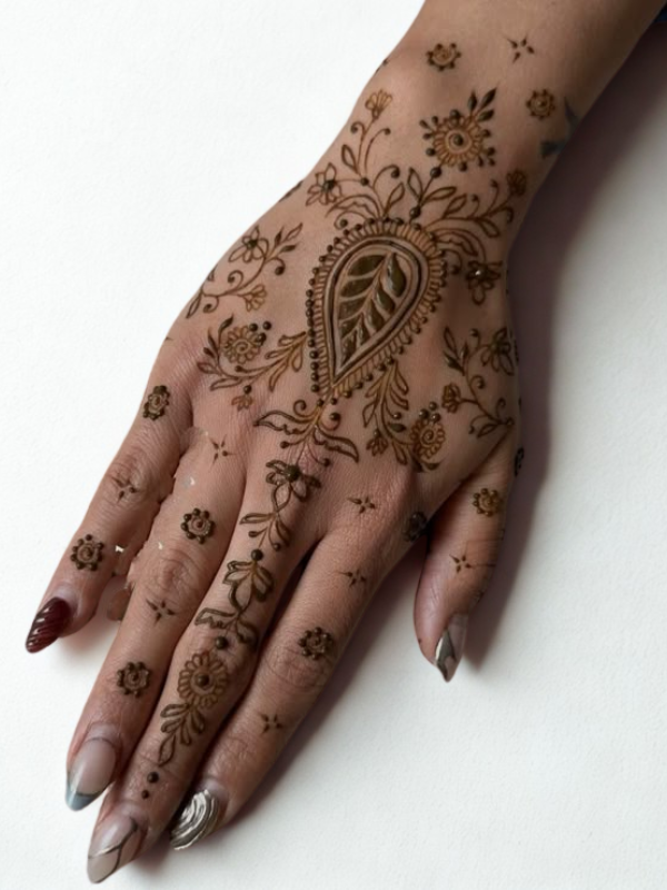 Intricate Mehndi design on the palm featuring a large central mandala with a butterfly motif, surrounded by fine floral and paisley patterns, with additional small butterfly and geometric accents on the fingers and wrist.