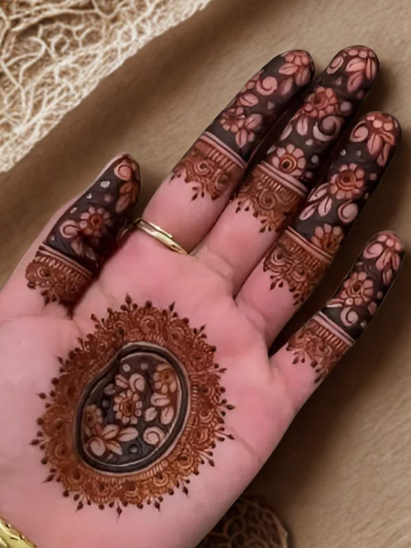 Elegant Mehndi design on the back of the hand featuring a detailed teardrop-shaped floral motif on the center, with intricate netted patterns and floral elements running along each finger