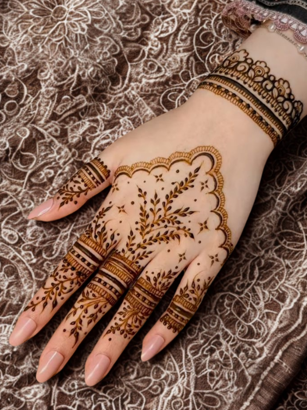 Intricate bridal Mehndi design on the back of the hand featuring a large circular mandala pattern connected to the wrist with dotted chains, and symmetrical scalloped motifs extending over the fingers