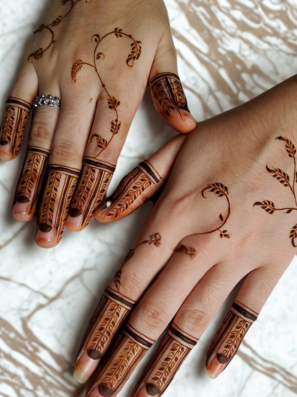 Intricate Mehndi design on the palm featuring a large central mandala with a butterfly motif, surrounded by fine floral and paisley patterns, with additional small butterfly and geometric accents on the fingers and wrist.