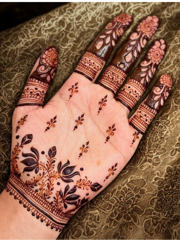Intricate bridal Mehndi design on the back of the hand featuring a large circular mandala pattern connected to the wrist with dotted chains, and symmetrical scalloped motifs extending over the fingers