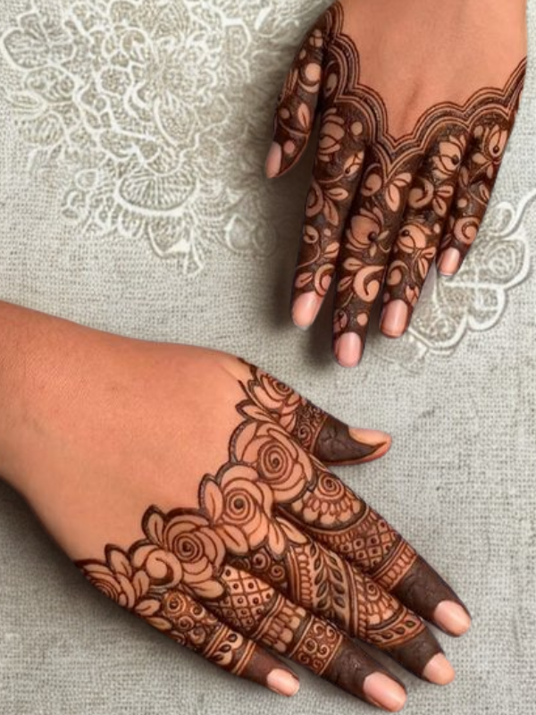 Elegant Mehndi design on the back of the hand featuring a detailed teardrop-shaped floral motif on the center, with intricate netted patterns and floral elements running along each finger