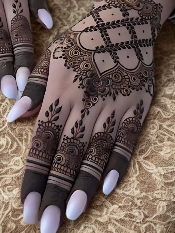 Intricate bridal Mehndi design on the back of the hand featuring a large circular mandala pattern connected to the wrist with dotted chains, and symmetrical scalloped motifs extending over the fingers