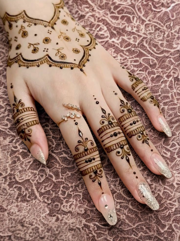 Elegant Mehndi design on the back of the hand featuring a detailed teardrop-shaped floral motif on the center, with intricate netted patterns and floral elements running along each finger