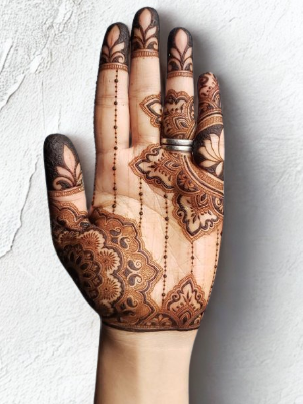 Intricate Mehndi design on the palm featuring a large central mandala with a butterfly motif, surrounded by fine floral and paisley patterns, with additional small butterfly and geometric accents on the fingers and wrist.