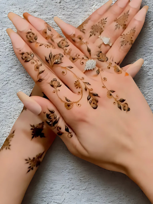 Elegant Mehndi design on the back of the hand featuring a detailed teardrop-shaped floral motif on the center, with intricate netted patterns and floral elements running along each finger
