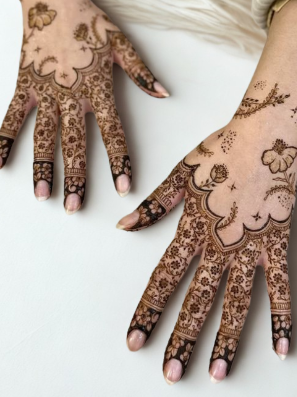 Intricate Mehndi design on the palm featuring a large central mandala with a butterfly motif, surrounded by fine floral and paisley patterns, with additional small butterfly and geometric accents on the fingers and wrist.