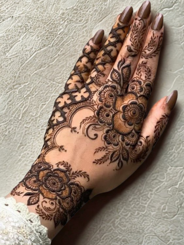 Elegant Mehndi design on the back of the hand featuring a detailed teardrop-shaped floral motif on the center, with intricate netted patterns and floral elements running along each finger
