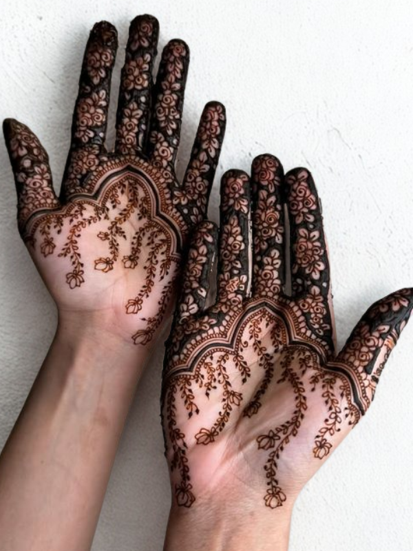 Intricate Mehndi design on the palm featuring a large central mandala with a butterfly motif, surrounded by fine floral and paisley patterns, with additional small butterfly and geometric accents on the fingers and wrist.